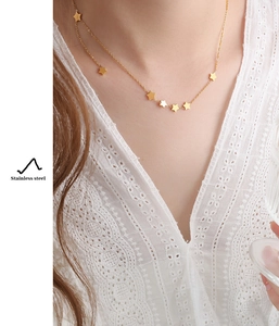 Detailed view of a gold-plated star pendant necklace worn by a model on lace fabric
