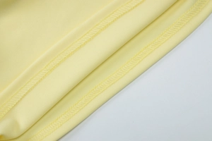 Detalle de la textura de la tela amarillo pálido y costuras finas en el top de verano