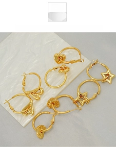 Detail view of gold titanium steel hoop earrings with star and heart charms on marble