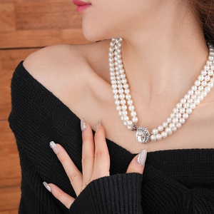 Dettaglio dell'elegante collana di perle bianche a tre fili con chiusura a diamante lucido