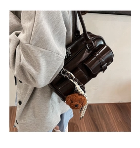 Detail view of coffee brown oil wax leather shoulder bag with plush bear charm