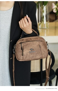 Detail of soft leather handbag for women featuring kangaroo logo and multi-zipper pockets