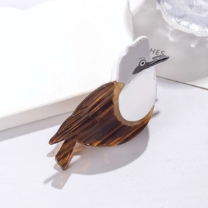 Macro detail of a bird-shaped acetate hair claw featuring white and amber pattern textures