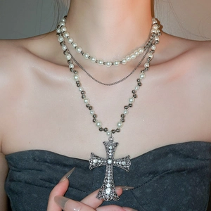 Detail of multi-layer necklace with beaded pearls, silver cross pendant and white rhinestones