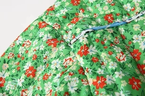 Macro detail of green floral quilted fabric with red flowers and contrast drawstring cord