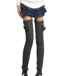 Detail of gray cable knit thigh-high leg warmers with matching fuzzy pom-poms on the side