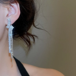 Dettaglio di lunghi orecchini a nappa d'argento con zirconi scintillanti su modella