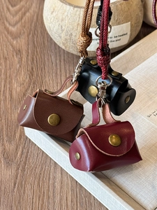 Detailed view of mini leather bags in brown, black, and burgundy with metal hooks