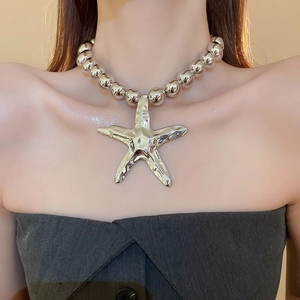 Macro shot of oversized silver starfish pendant on a chunky beaded metallic necklace