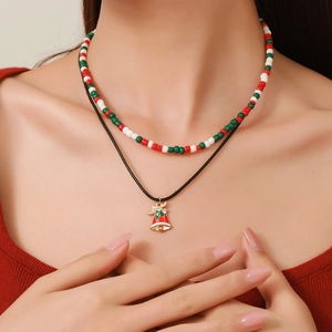 Close-up of double-layer Christmas necklace with red beads and a festive bell pendant