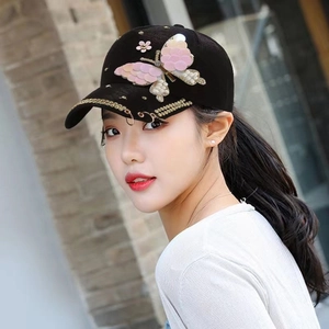 Détail de la casquette avec papillon en paillettes, clous dorés et anneaux de visière