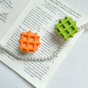 Dettaglio di supporti per telefono a forma di waffle arancione e verde su una pagina