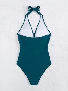 Detail of dark green one-piece swimsuit featuring halter bow and removable chest pads