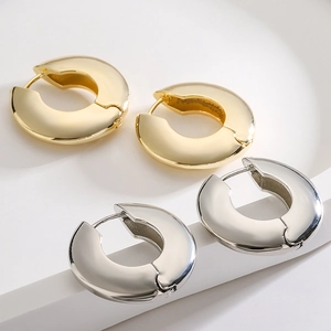 Set di orecchini a cerchio spessi in oro e argento lucido su un espositore minimalista
