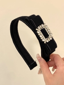 Détail d'un serre-tête en velours noir avec boucle carrée en strass et nœud élégant