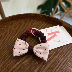 Retro wine red polka dot bow scrunchie on a dark wooden tray with elegant fabric texture
