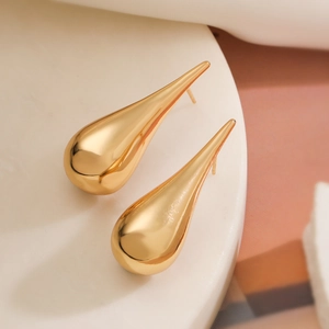 Minimalist teardrop shaped 18K gold plated copper stud earrings on a white marble base