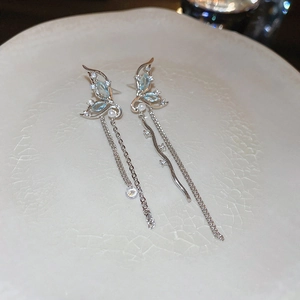 Détail de boucles d'oreilles papillon à pompons avec cristaux bleu clair et argent