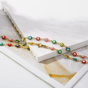 Detail of colorful enamel evil eye beads on a golden chain bracelet with lobster clasp