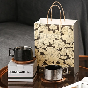 Detailed view of black and silver ceramic mugs with premium wooden bases and gift packaging