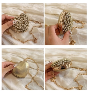 Détail d'un sac de soirée doré en forme de cœur orné de strass brillants et d'une chaîne
