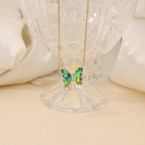 Elegant gold butterfly necklace with teal crystals draped over a crystal wine glass