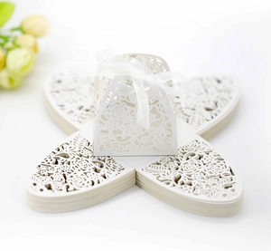 Macro shot of laser-cut wedding favor box with white ribbon bow and flat paper board