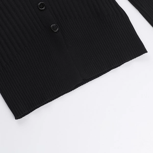 Detail of black ribbed knit cardigan showing the hemline and matching round buttons