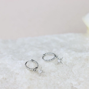 Silver hoop earrings with beaded texture and zircon star pendant on mineral background