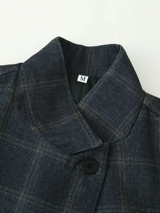 Detailed view of dark grey plaid blazer lapel with M-size label and black button