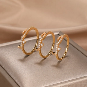 Close-up of three rose gold rings with leaf vine patterns and inlaid cubic zirconia crystals