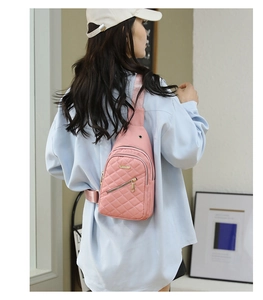 Detailed back view of a pink quilted nylon chest bag with golden zippers worn by model