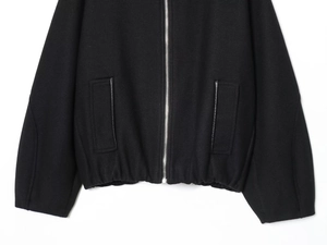 Detail of black wool jacket with metal zipper closure and leather trimmed side pockets