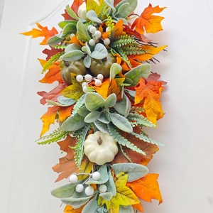 Macro detail of autumn harvest wreath with orange pumpkins and colorful maple leaves