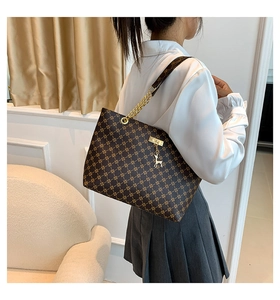 Borsa tote marrone con stampa geometrica, catena dorata e ciondolo a cervo indossata da modella