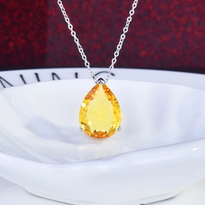 Elegant silver necklace featuring a pear-cut yellow gemstone pendant on a ceramic dish