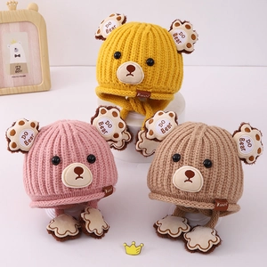 Detailed view of three bear-shaped knitted hats for babies with ear flaps and paw drawstrings