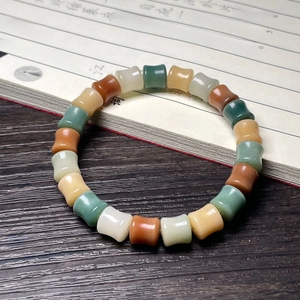 Close-up of bamboo-shaped Bodhi root beads in multiple colors on a wooden surface