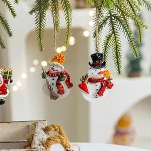Festive resin snowman ornament hanging on Christmas tree branch with warm bokeh lights