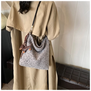 Detail of grey wool knit tote bag with black strap and brown dog leather charm pendant