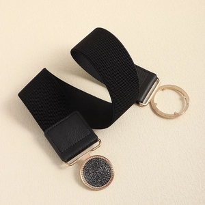 Close-up of black elastic belt with golden round buckle and textured circular insert