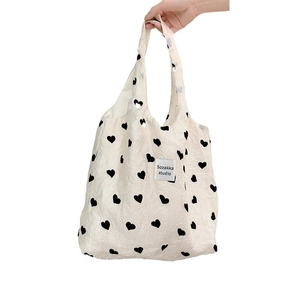 Cream textured canvas shoulder bag with heart pattern and minimalist branding