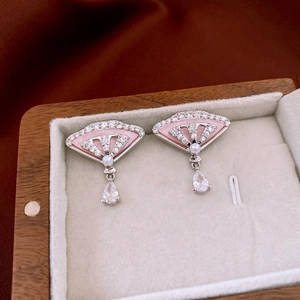 Détail de boucles d'oreilles éventail avec perle, incrustation rose et goutte en zircon