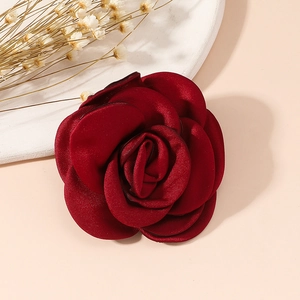 Detail of a deep red fabric rose brooch crafted with multi-layer silk texture petals