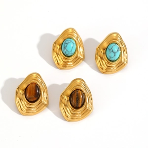 Gros plan de boucles d'oreilles vintage en or avec turquoise et œil de tigre