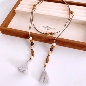 Detailed shot of ethnic wooden beads and grey tassels on a velvet display tray