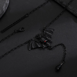 Gothic black bat necklace with red ruby stone pendant on textured background