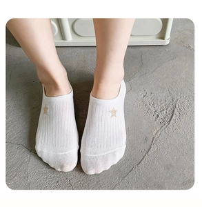 Close-up of white cotton low-cut socks with gold star embroidery and ribbed texture