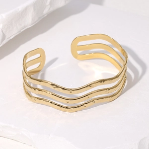 Macro detail of 18K gold plated wave bangle showing triple layered texture and hammer finish