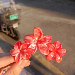 Detail showing the red and white marble texture of the floral claw hair clip